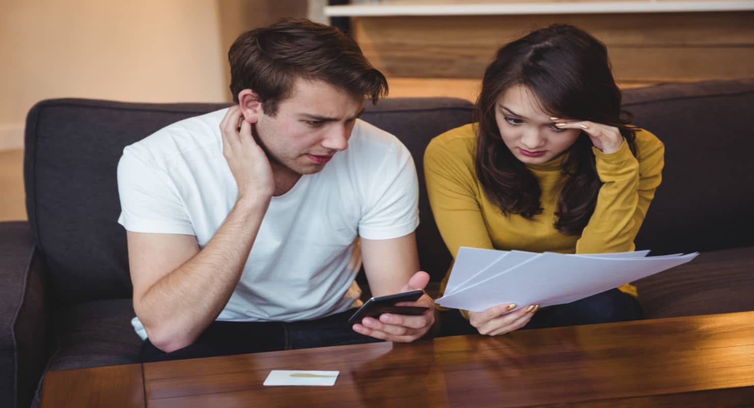 Couple sitting on sofa discussing with financial adviser