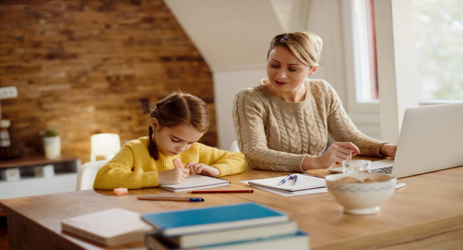 Small girl writing in notebook while her mother watches