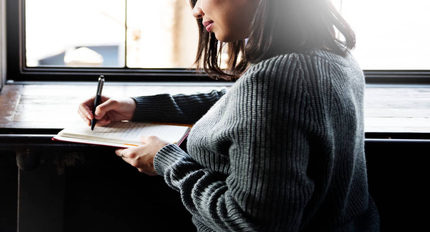 Asian woman writing on a notebook